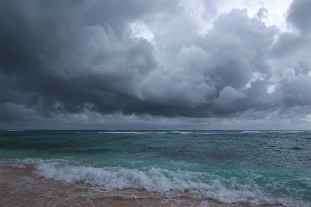 Dramatic storm clouds gathering over the calm, Caribbean Sea on a beach in Jamaica during a typical August afternoon.