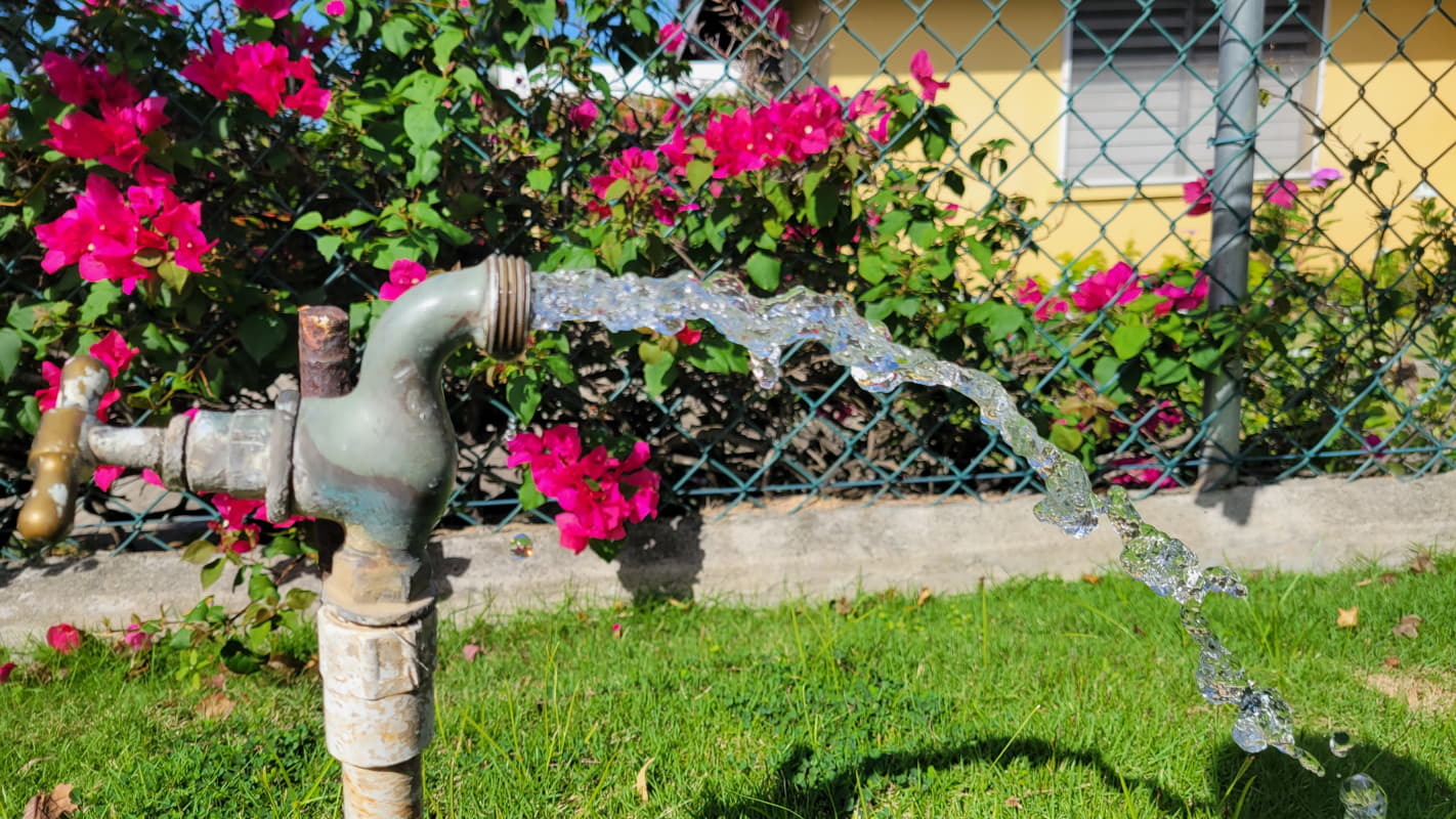 Outdoor water pipe in Kingston, Jamaica with drinking water flowing from it.