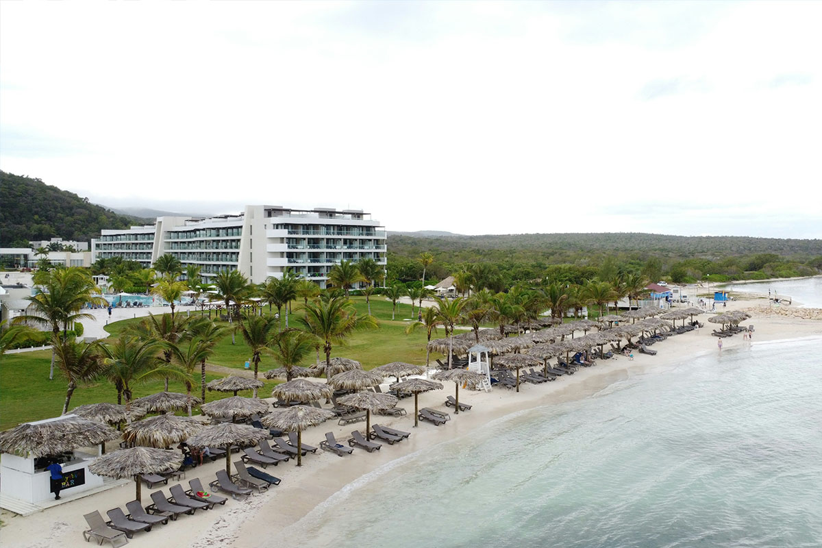 A picturesque beachside shot of a resort in Jamaica with palm trees.