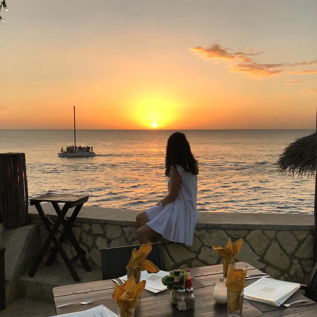 A woman gazing at the sunset from the dining area at Ivan’s Restaurant in Negril.