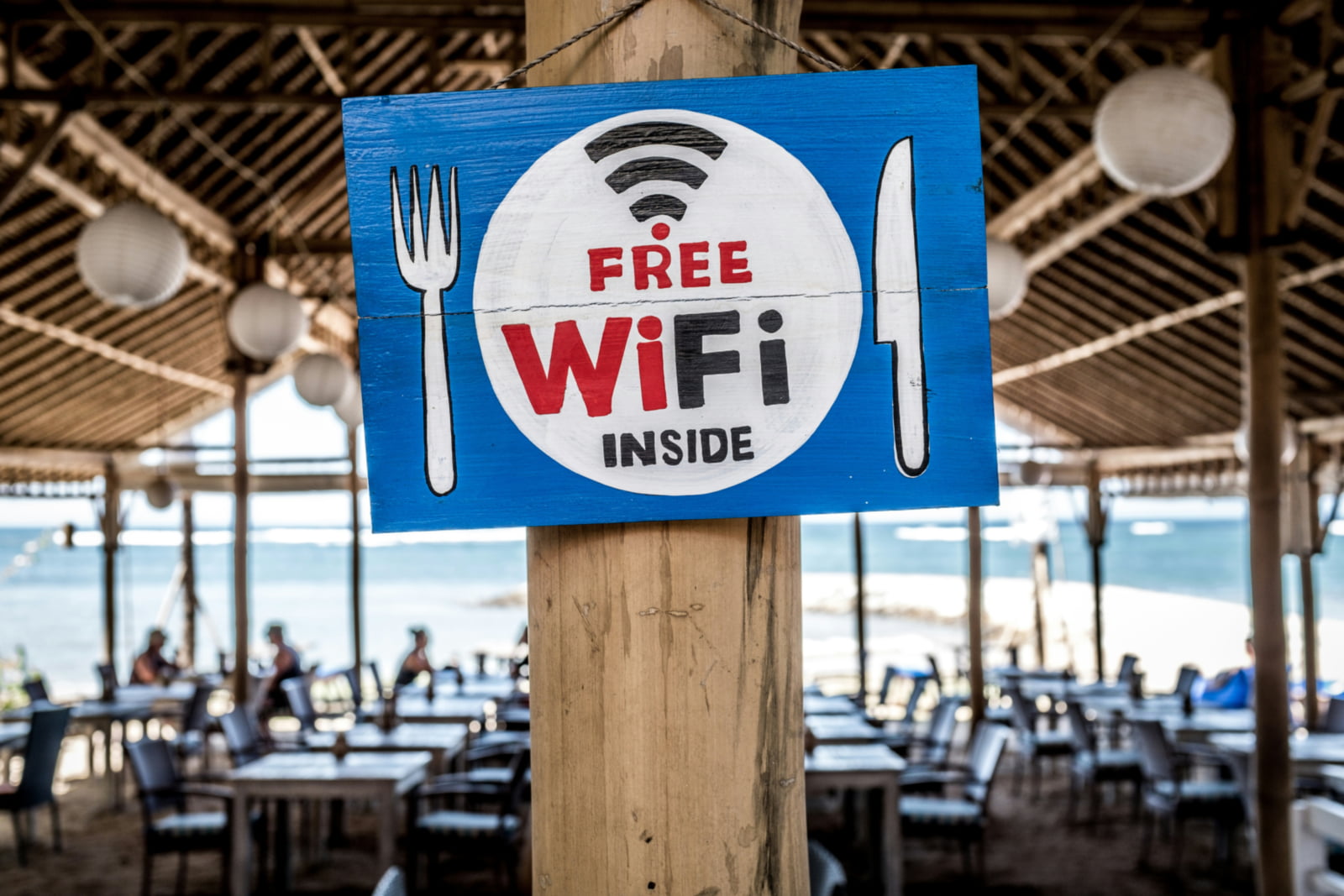 A welcoming sign on a wooden stand advertising free Wi-Fi to customers at a beachfront restaurant in Jamaica.