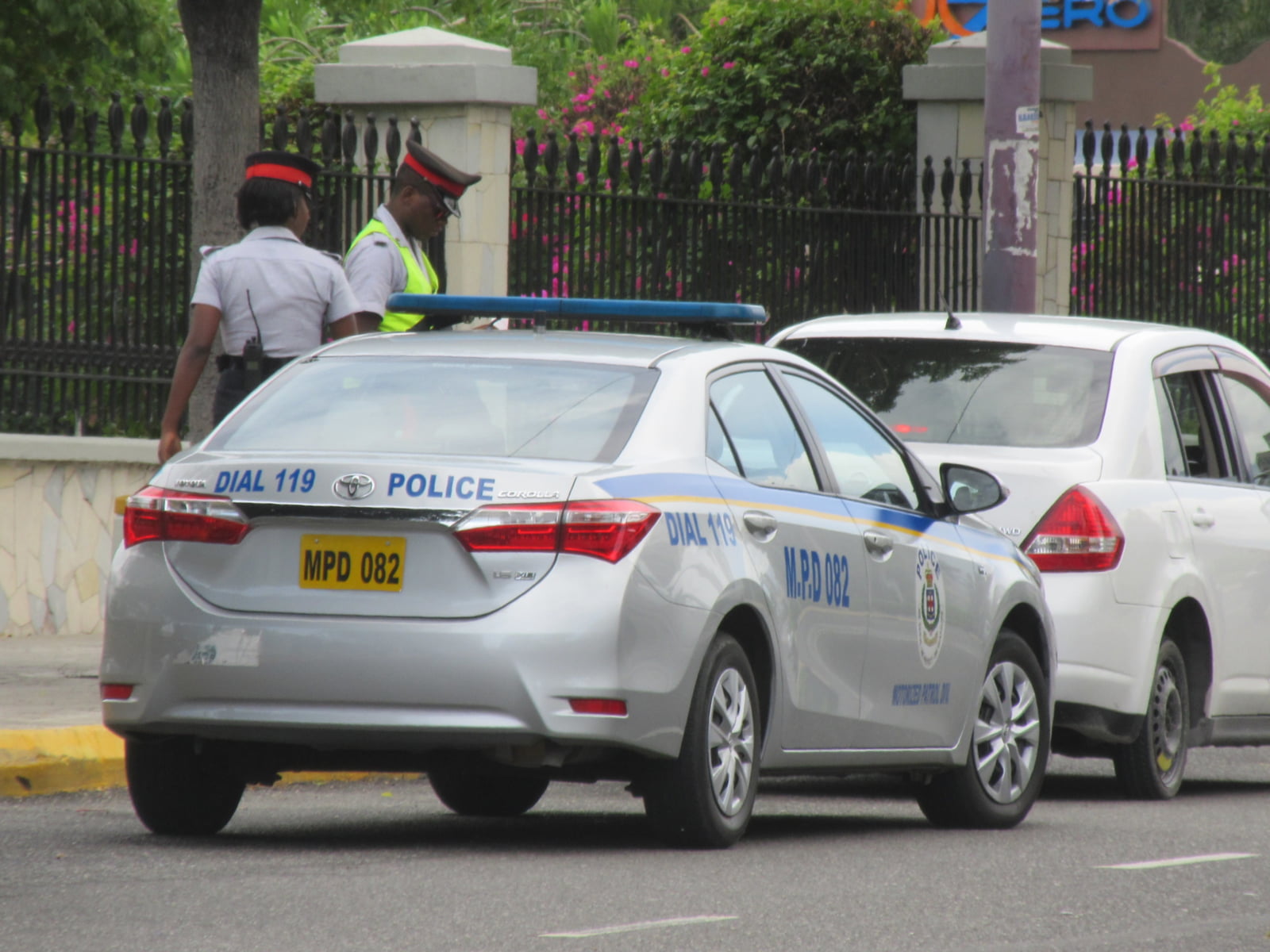 wo Jamaican police officers conducting a routine traffic stop on a road in Jamaica to ensure driver safety.
