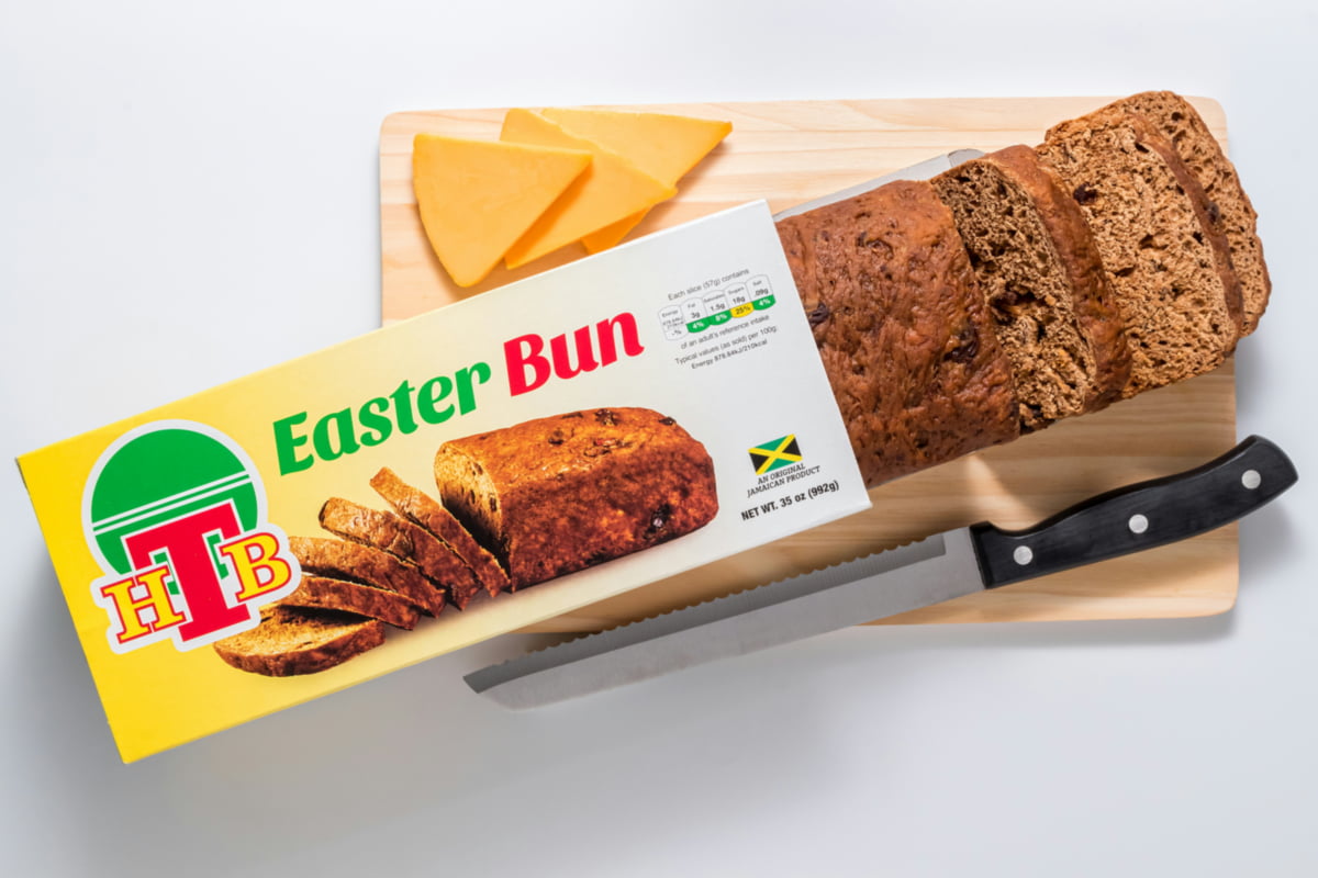 A freshly sliced Jamaican Easter bun served alongside thick slices of Tastee cheese, a traditional holiday pairing.