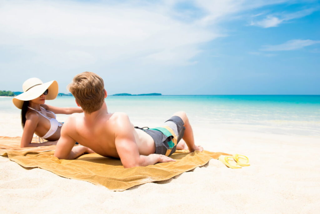 Tourists lying on the sand in Jamaica in August, enjoying hot tropical weather and sunshine