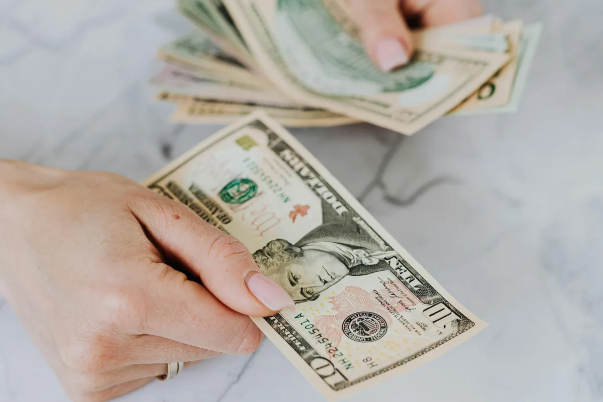 Person holding a 10 dollar bill to illustrate a good tip in Jamaica